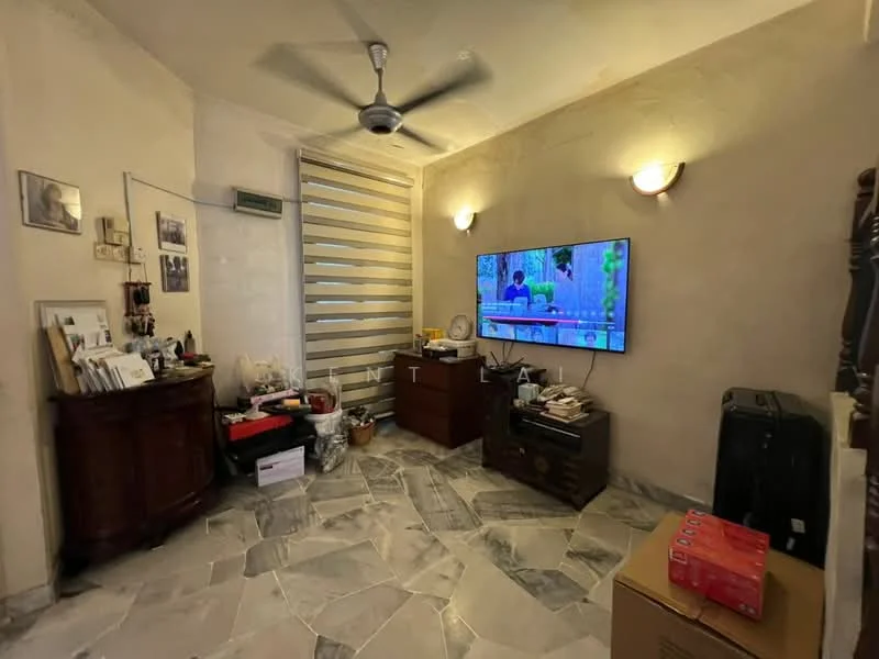 Living features: marble flooring, cream painted walls, ceiling fan, wall-mounted TV, wooden TV console, decorative wall sconces, storage cabinet, various decorative items, stacked boxes, luggage, window with blinds.