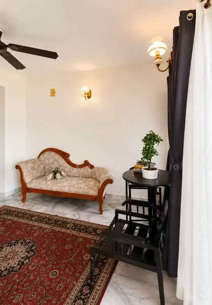 Living features: 3-seater vintage sofa with floral upholstery, black wooden side table, 2 wooden dining chairs, area rug with intricate pattern, white marble flooring, ceiling fan, wall-mounted sconces, floor-to-ceiling curtains, potted plant on side table; style: traditional.