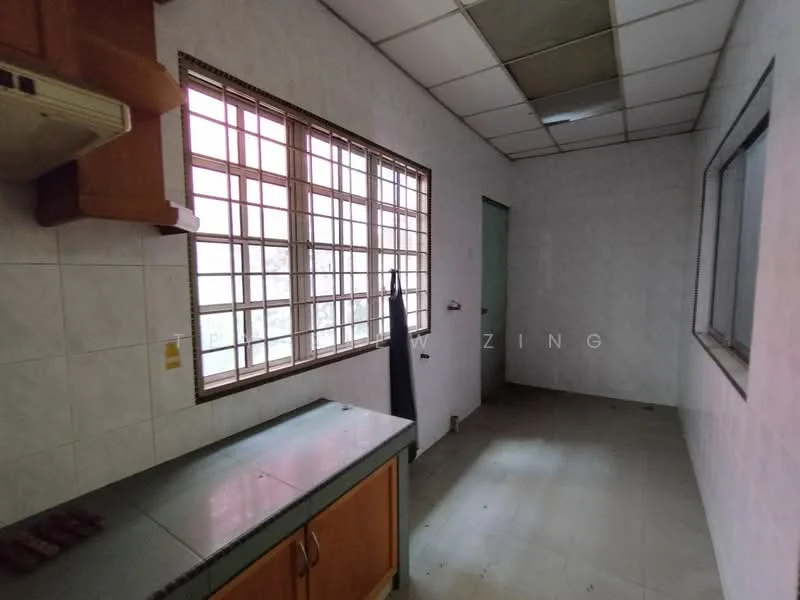 Kitchen features: white tiled walls, grey countertop, wood cabinetry, single window with metal grille, vinyl flooring, ceiling tiles, exposed light fixtures, door leading to another room.
