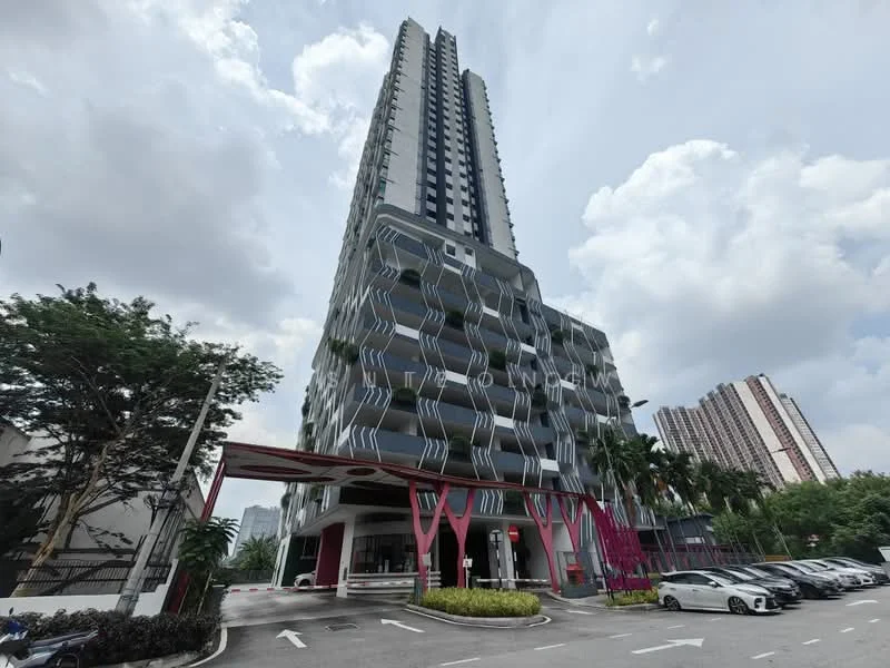 Exterior type: high-rise condominium; features: glass curtain wall, projecting balconies, red accent columns at entrance, manicured landscaping, paved driveway, multiple parking spaces, surrounded by palm trees, adjacent to other high-rise buildings; style: modern.