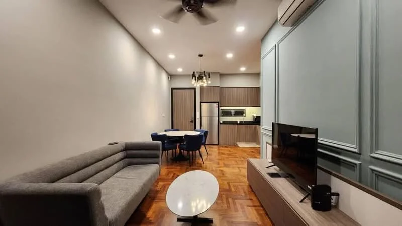 Living features: 3-seater fabric sofa in grey, coffee table with oval top, wall-mounted TV, TV console, ceiling fan with light, recessed downlights, wooden flooring, decorative wall paneling, air conditioning unit; style: modern. Dining features: round dining table, upholstered dining chairs in blue, kitchen area visible in background, refrigerator, built-in oven, microwave; style: modern.