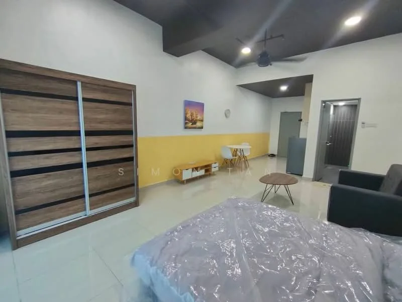 Room features: queen-size bed with grey bedding, wooden wardrobe with sliding doors, grey fabric sofa, round coffee table, white dining table with two chairs, yellow painted accent wall, white walls, tile flooring, ceiling fan, wall clock, door to bathroom, door to hallway; style: modern.