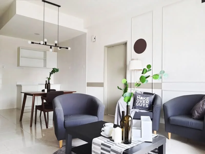 Living features: two grey fabric armchairs, black coffee table, decorative throw pillow with text, green plant in vase, white ceramic vase, bottle on table, wall-mounted light fixture, recessed ceiling lights, white painted walls, tile flooring, dining area visible in background, open-plan layout; style: modern. Dining features: wooden dining table for four, four dining chairs, white cabinetry in background, minimalist decor; style: modern.