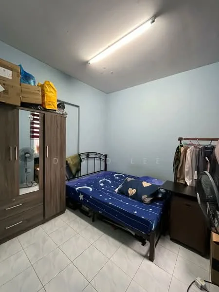 Bedroom features: single bed with blue bedding featuring moon and star pattern, wooden wardrobe with sliding doors, black bedside table, standing fan, white tiled flooring, light blue painted walls, fluorescent ceiling light, clothes rack with hanging clothes.