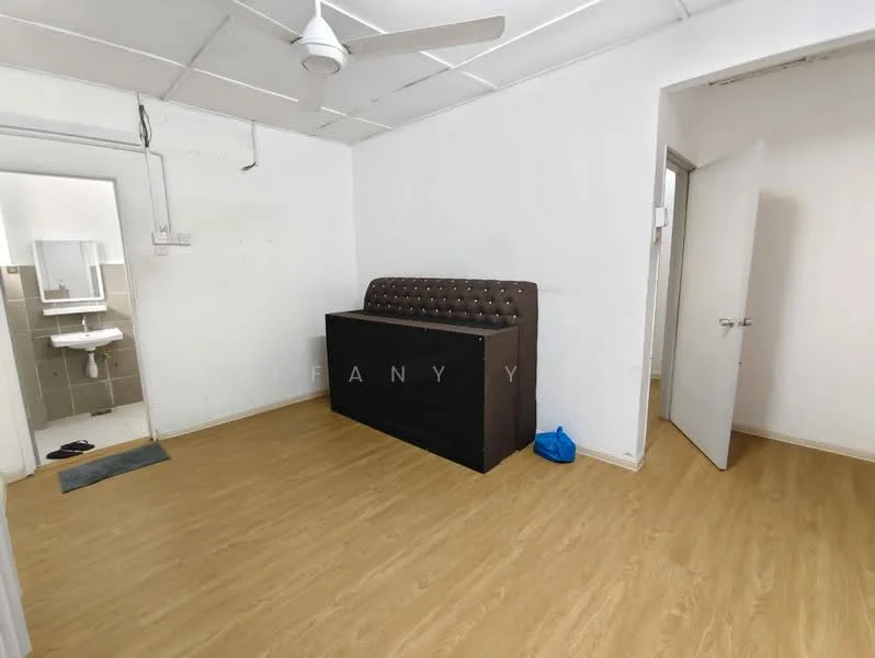 Room features: light wood laminate flooring, white painted walls, ceiling fan, upholstered headboard, black bed frame, door leading to bathroom, door leading to hallway, small area rug, blue plastic bag on floor; style: minimalist.