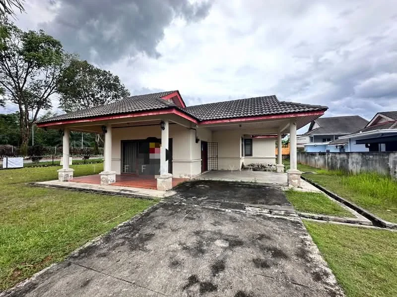 Exterior type: detached bungalow; features: single-storey, pitched tile roof, cream painted facade, red trim on roof, front porch with columns, manicured lawn, concrete pathway, surrounded by greenery, driveway, fenced perimeter; style: traditional.