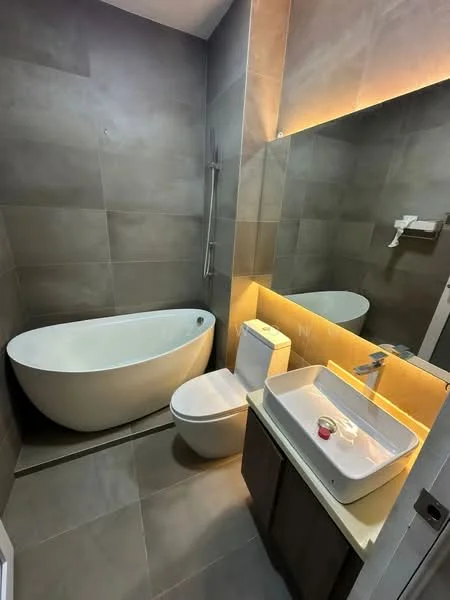 Bathroom features: freestanding bathtub, one-piece toilet, single-sink vanity with countertop, mirror with backlighting, wall-mounted faucet, tile cladding on walls, grey tile flooring, shower with handheld showerhead, built-in shelving, ambient lighting, dark wood cabinetry; style: modern.