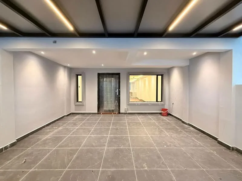 Room features: grey tiled flooring, white painted walls, exposed beam ceiling with recessed lighting, two small windows, double glass door entrance, wall-mounted light fixtures, open layout, no visible furniture; style: modern.