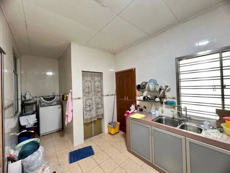 Kitchen features: light grey cabinetry, brown countertop, double-bowl stainless-steel sink, chrome pull-down faucet, tile backsplash, ceramic tile flooring, washing machine, window with security bars, refrigerator, kitchen towel hanging, cleaning supplies in yellow bucket, blue mat on floor, wall-mounted shelves, wall tiles with white finish.