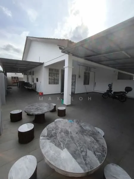 Exterior type: detached bungalow; features: flat roof, white painted facade, outdoor seating area with marble-top tables, wooden stools, concrete flooring, covered carport, motorcycle parked, surrounded by walls, large windows, open space; style: modern.