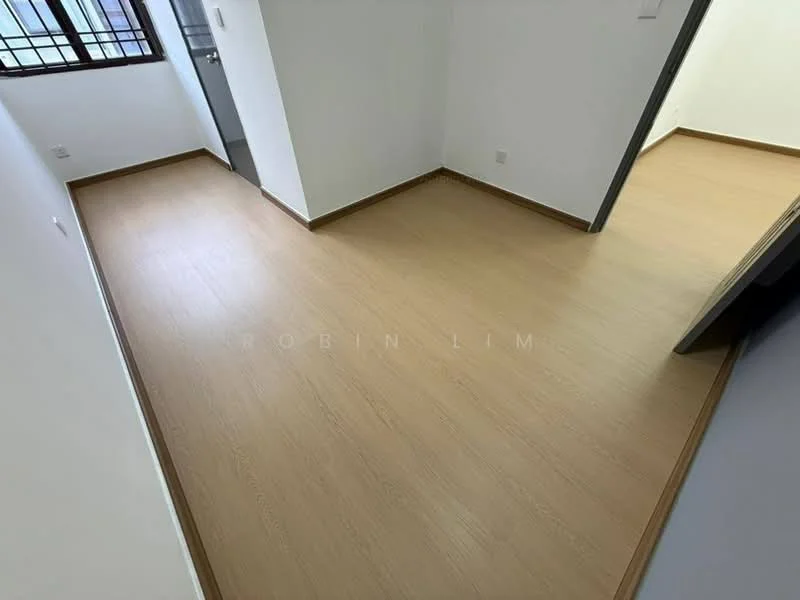 Room features: light wood laminate flooring, white painted walls, brown trim around flooring, corner windows, doorway leading to another room, no visible furniture or decor; style: modern.