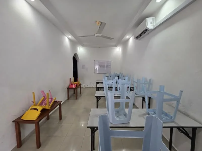 Room features: white painted walls, polished tile flooring, ceiling fan, recessed downlights, 2 tables with metal legs, stacked plastic chairs in yellow and pink, air conditioning unit on wall, whiteboard on wall.