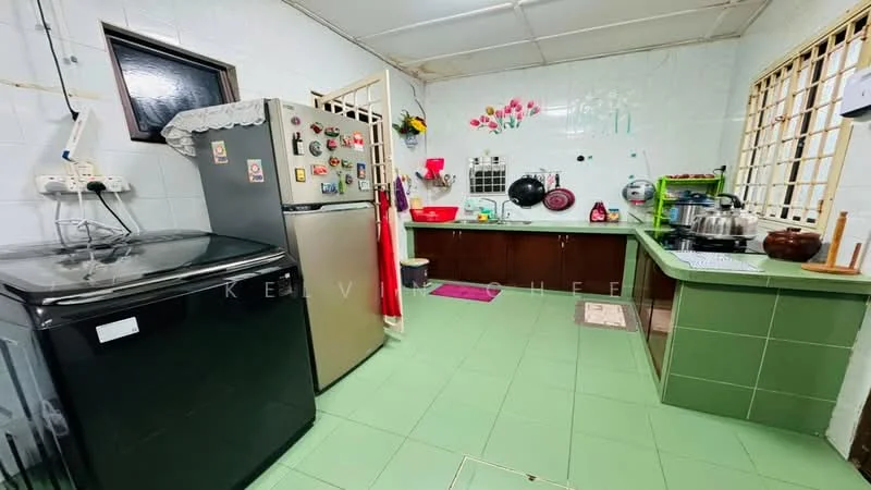 Kitchen features: green tiled flooring, white tiled walls, stainless-steel fridge, black front-load washing machine, wooden countertop, sink with faucet, wall-mounted cabinets, decorative wall art, kitchen utensils on countertop, cooking pots, open shelving, window with security bars.