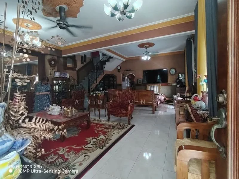 Living features: cream painted walls, white ceiling with recessed downlights, 5-blade ceiling fan, large wall-mounted TV, wooden coffee table, upholstered armchairs, sofa set with decorative cushions, area rug with intricate pattern, wooden sideboard, decorative plants in ceramic pots, large windows with yellow curtains, staircase with wooden railing; style: traditional.