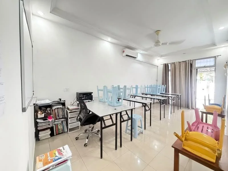 Room features: white painted walls, glossy tile flooring, ceiling fan, recessed downlights, large windows with sheer curtains, multiple tables with chairs stacked on top, black office chair, air conditioning unit, bookshelves with visible books and materials; style: modern.