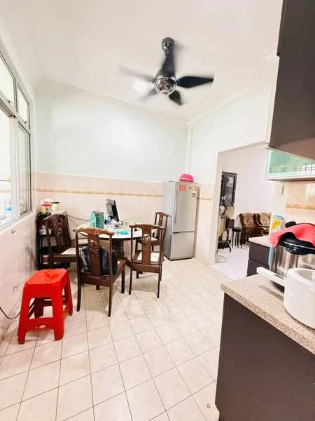 Kitchen features: white painted walls, tile flooring, 5-blade ceiling fan, dining table with chairs, red plastic stool, stainless-steel fridge, kitchen countertop, kitchen cabinets, window with natural light, microwave, cooking appliances, sink, decorative items on table.