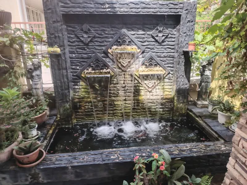 Exterior type: landscape garden; features: decorative stone water feature, three-tiered fountain, black stone facade, surrounding greenery, potted plants, mature trees, water flowing from fountain, stone-paved area, ornamental sculptures; style: tropical-modern.