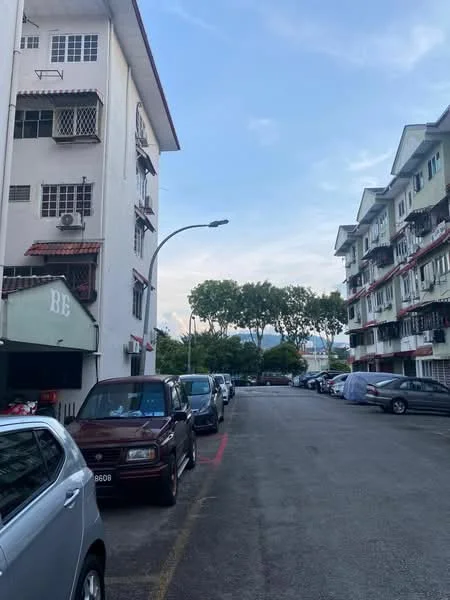 Exterior type: low-rise apartment block; features: white painted facade, red tiled roof, balconies with railings, surrounded by trees, parking spaces visible, street lighting, asphalt road, multiple vehicles parked, clear sky, urban setting; style: modern.