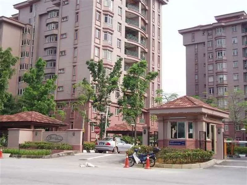 Exterior type: mid-rise condominium; features: pink painted facade, gabled roof with tiles, guard house at entrance, manicured landscaping, mature trees, paved driveway, parking spaces visible, multiple storeys, entrance signage, surrounded by greenery; style: modern.