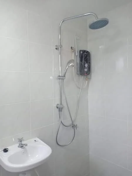 Bathroom features: white tiled walls, white ceramic sink, chrome basin mixer faucet, shower head with adjustable height, wall-mounted shower control, electric water heater, glass shower enclosure, white tiled flooring; style: modern.