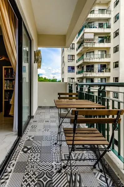 Balcony features: outdoor dining table with wooden slats, metal folding chairs, decorative patterned floor tiles, glass sliding door, railing with metal balusters, view of neighboring buildings, curtains in light fabric, overhead ceiling; style: modern; view: city.