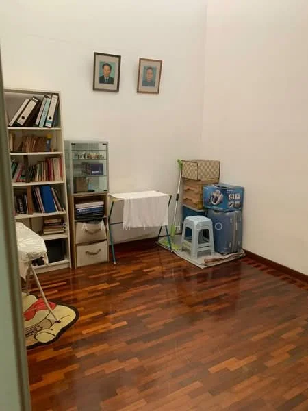 Room features: wooden flooring, white painted walls, bookshelf with books and files, glass display cabinet, folding table, plastic stool, laundry drying rack, water dispenser, framed portraits on the wall.