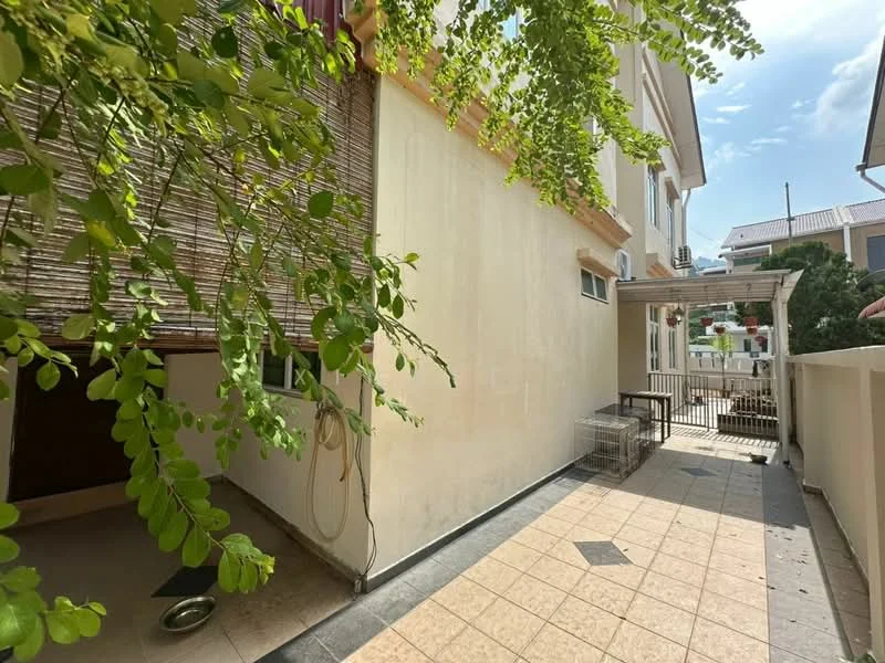 Exterior features: paved walkway, yellow painted walls, green foliage from trees, outdoor seating area, fenced area, windows visible on building, sunny weather, clear blue sky.