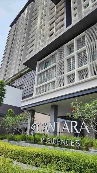 Exterior type: high-rise condominium; features: glass curtain wall, grey painted facade, recessed balconies, landscaped garden with shrubs, signage with 'CANTARA RESIDENCES', multiple storeys, modern architectural design; style: modern.