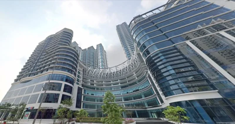 Exterior type: high-rise condominium; features: glass curtain wall, exposed concrete facade, recessed balconies, vertical fins, feature lighting at night, manicured landscaping, surrounded by mature greenery; style: modern.