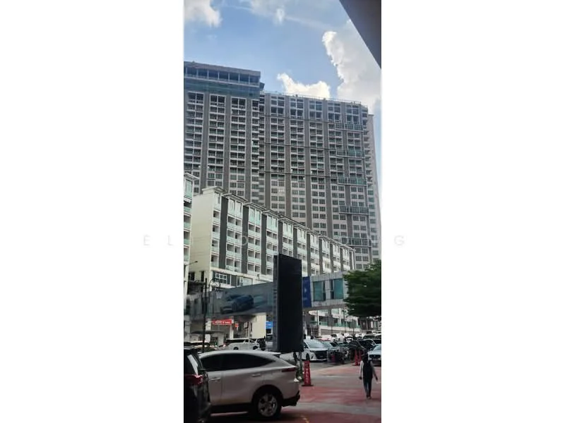 Exterior type: high-rise condominium; features: glass curtain wall, multiple balconies, parking lot with vehicles, surrounding greenery, urban context with nearby buildings, approximately 20-storey high-rise; style: modern.