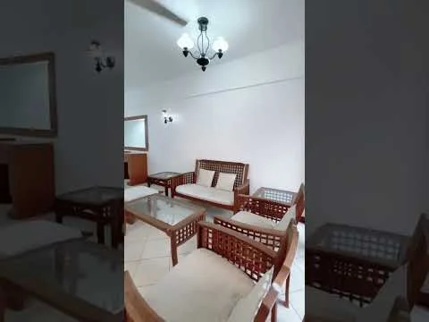 Living features: wooden coffee table, 3-seater wooden sofa with cushions, 2-seater wooden sofa with cushions, ceiling light fixture with multiple bulbs, wall-mounted mirror, tiled flooring, white painted walls, decorative wall sconce; style: traditional.