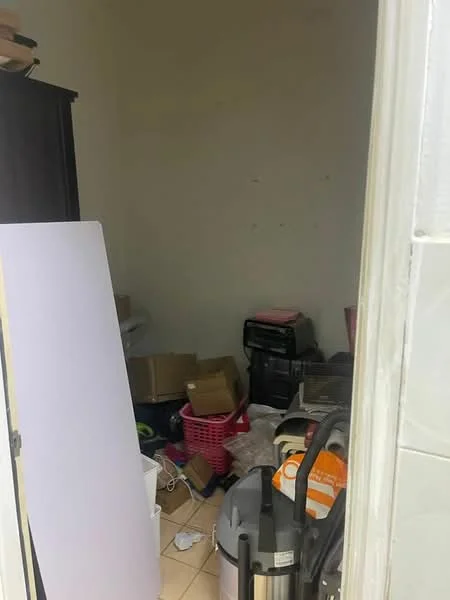 Room features: tile flooring, white painted walls, cluttered with boxes, vacuum cleaner, plastic storage bins, waste basket, unidentified furniture, messy appearance.