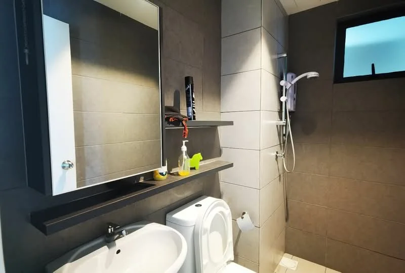 Bathroom features: grey tiled walls, white ceramic sink, chrome basin mixer faucet, framed mirror, white toilet, shower with glass partition, handheld shower head, wall-mounted shelf, grey tiled flooring, soap dispenser, toothbrush holder, shower gel bottle; style: modern.