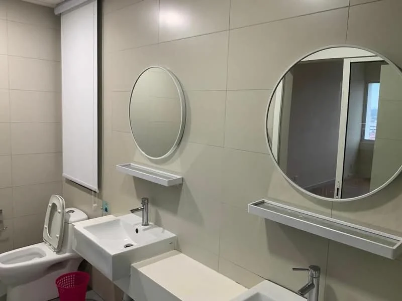 Bathroom features: two circular mirrors, two white sinks, chrome basin mixers, white tiled walls, light-colored flooring, one-piece toilet, white countertop, roller blinds, pink waste bin; style: modern.