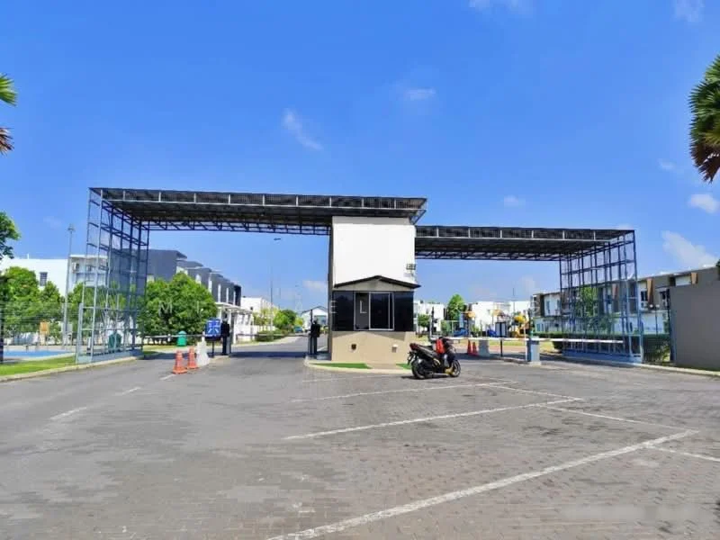 Exterior type: main entrance gate; features: guard house at entrance, gated entry, paved driveway, landscaped greenery, parking spaces, security booth, canopy structure, surrounded by residential buildings; style: modern.