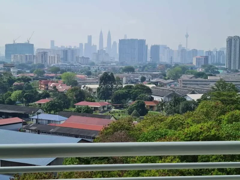 Exterior features: city skyline view, lush greenery in foreground, urban landscape, mixed residential and commercial buildings, distant high-rise buildings, visible construction cranes, clear sky; style: modern.