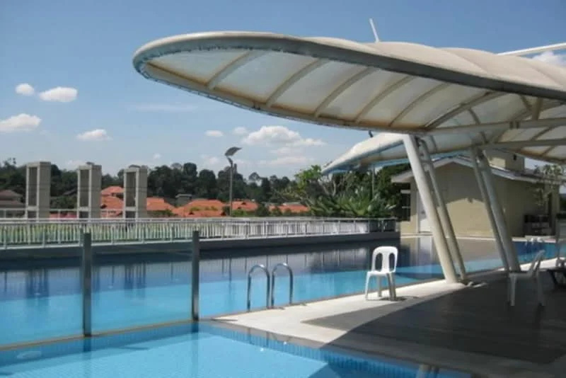 Exterior type: swimming pool deck; features: infinity pool, pool deck with loungers, canopy structure over pool area, surrounding greenery, city skyline view, outdoor lighting fixtures, decking area, railings around pool; style: modern.