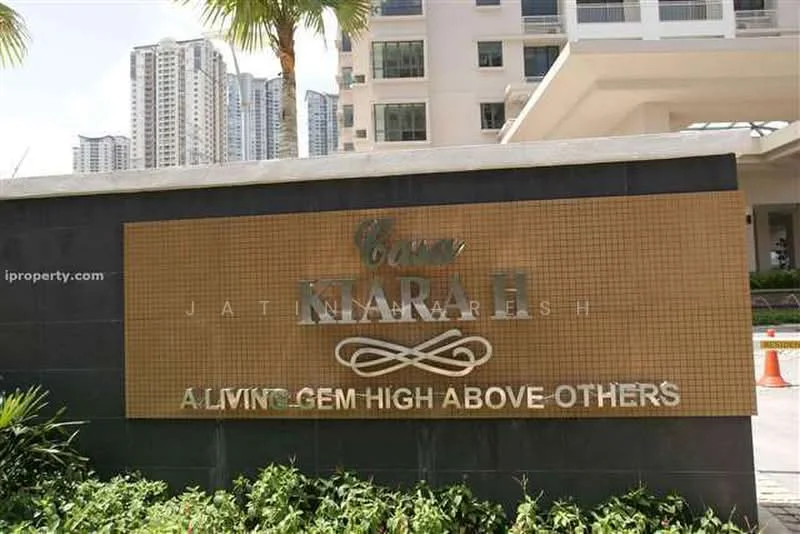 Exterior type: high-rise condominium; features: signage with gold lettering, landscaped entrance, surrounding greenery, modern architectural design, paved walkway, visible high-rise buildings in background; style: contemporary.