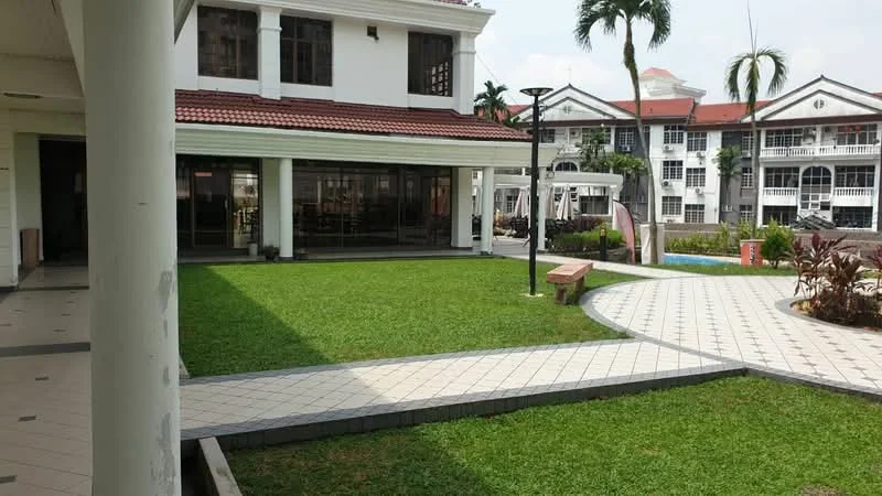 Exterior type: clubhouse; features: manicured lawn, paved walkway, landscape garden, outdoor seating area, swimming pool in background, palm trees, white painted facade, red tiled roof, glass sliding doors, outdoor lighting, decorative benches; style: modern.