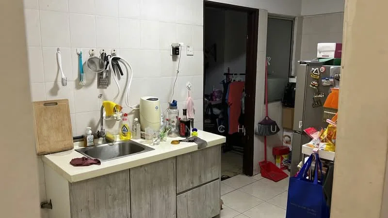Kitchen features: single-bowl stainless-steel sink, chrome pull-down faucet, wooden cabinetry with grey finish, white tiled walls, white tiled flooring, kitchen countertop, wall-mounted utensils rack, various kitchen appliances visible, open shelving, floor-mounted storage cabinet. Room features: doorway leading to another room, visible floor tiles, hanging clothes rack, various items on the floor.
