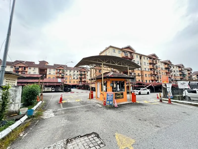 Exterior type: low-rise apartment block; features: main entrance gate with guard house, covered drop-off area, parking lot with marked spaces, surrounding low-rise buildings, paved driveway, traffic cones for parking management; style: modern.
