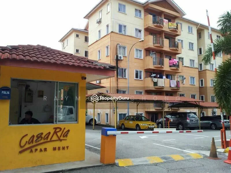 Exterior type: low-rise apartment block; features: yellow painted facade, red tiled roof, balconies with clothes hanging, covered parking area, security booth at entrance, guard house, surrounded by greenery, driveway with interlocking pavers; style: modern.