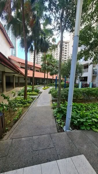 Exterior type: landscape garden; features: paved walkway, manicured lawn, mature palm trees, tropical landscaping, surrounding greenery, low-rise building facade, outdoor seating area, playground equipment visible in background; style: modern.