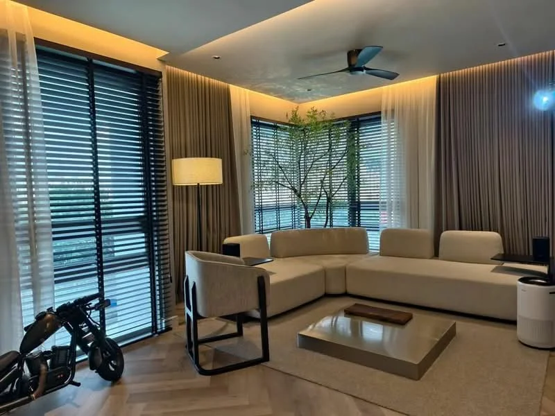 Living features: L-shape sectional sofa in beige, coffee table, area rug with geometric pattern, floor-to-ceiling windows, blackout curtains, 5-blade ceiling fan with light, decorative plant, wooden flooring, wall-mounted lighting, side table, decorative wall panels; style: modern; view: city.