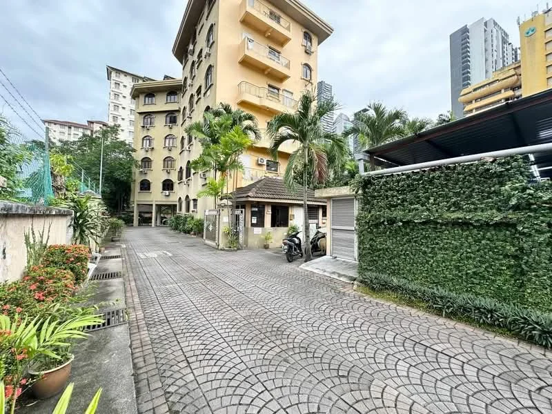 Exterior type: low-rise apartment block; features: paved driveway, landscaped greenery, mature palm trees, security gate, motorcycle parking, surrounding buildings, fenced perimeter, two-storey building, balconies on upper floors, interlocking paver stones; style: modern.