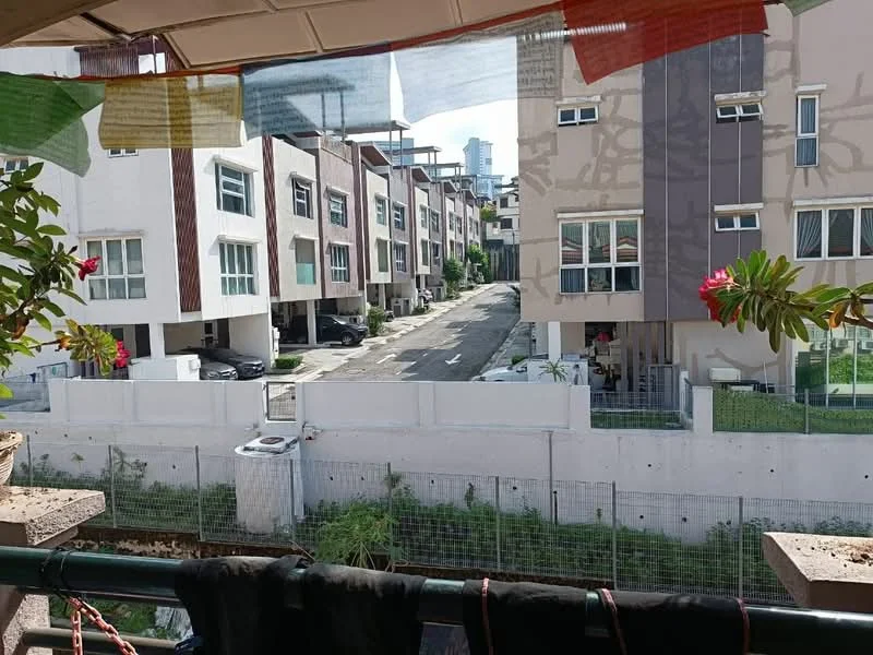 Room features: balcony with railing, potted plants, clothes hanging on a line, view of neighboring houses, view of street, fenced area below, greenery visible, sunlight illuminating the space; view: street.