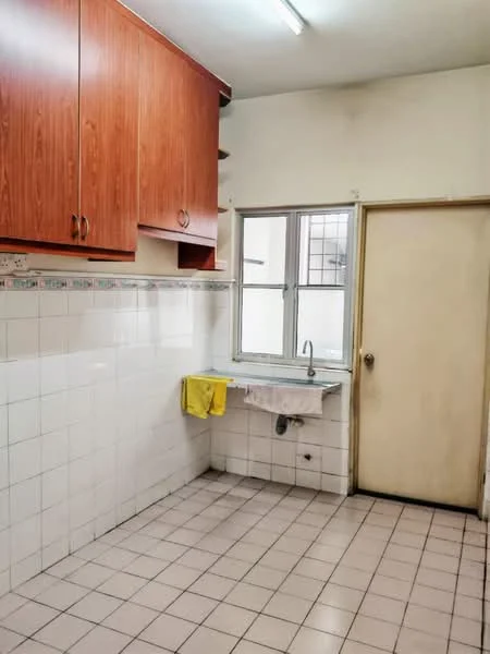 Kitchen features: wooden cabinetry in light brown, white tiled walls, grey tiled flooring, single-bowl stainless-steel sink, chrome faucet, window with grid pattern, yellow dish towel, door leading to another room.