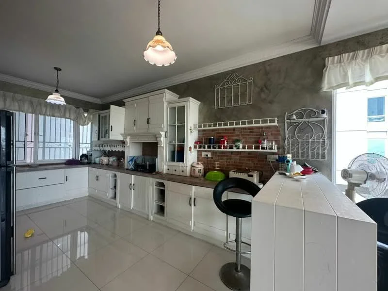 Kitchen features: white cabinetry with glass-front upper cabinets, grey accent wall, marble countertop, stainless-steel fridge, built-in oven, freestanding range oven, single-bowl stainless-steel sink, chrome pull-down faucet, tile backsplash, bar counter with stools, pendant lighting, white ceramic tile flooring, window with sheer curtains, wall-mounted fan; style: modern.