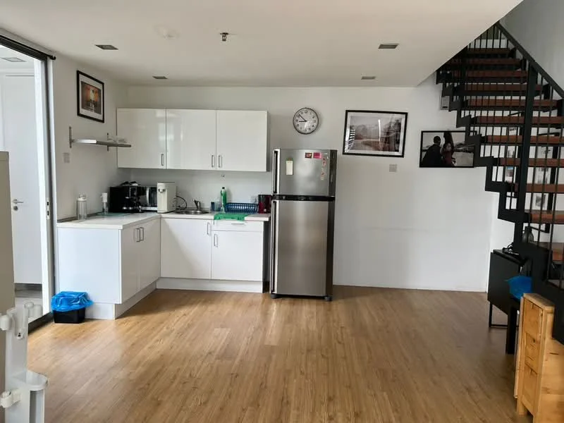 Kitchen features: white cabinetry, stainless-steel fridge, built-in oven, 4-burner gas hob, single-bowl stainless-steel sink, chrome pull-down faucet, white countertop, wooden flooring, wall clock, window with sheer curtains, decorative artwork on walls, open shelving; style: modern.