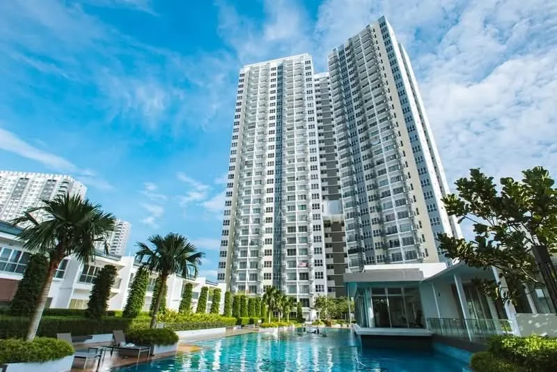 Exterior type: high-rise condominium; features: glass curtain wall, white painted facade, recessed balconies, infinity pool, pool deck with loungers, manicured landscaping, palm trees, tropical landscaping, surrounded by greenery, modern architectural design; style: modern.
